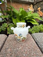Miniature Aynsley Cottage Garden bone china vase shown outdoors on a brick surface with greenery background. Front view showing floral pattern and handles.