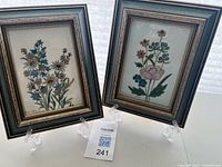 Two framed enamel on copper paintings on display stands