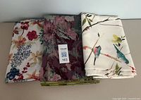 Three folded tablecloths showing their patterns side by side