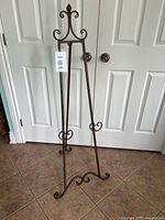 Full view of wrought iron floor easel standing on tile floor