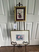 Both framed floral prints on easel showing relative sizes and frames