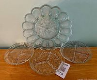 All four crystal serving pieces arranged: deviled egg plate at back, three 3-section plates in front
