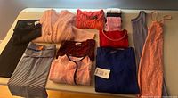 Folded assortment of tops, cardigans, pants, dress