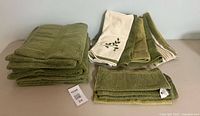 Stack of green bath towels left, mixed hand towels right, washcloths front