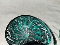 Close-up image of the seashell-shaped aqua glass dish with visible silver flecks inside the glass.