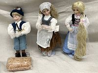 Three Ashton Drake dolls displayed: Little Boy Blue, Cinderella, and Rapunzel, all standing with detailed costumes and props.