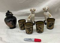 Front view showing two dog figurines, four sake mugs, and ginger jar with lid placed next to a red Sharpie for scale.