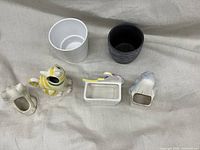 Top and front view of six ceramic planters including animal shapes and textured cylindrical forms on a light fabric background.