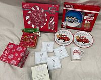 Full view of all items in the lot including boxed plates, coasters, mug, and napkins on a beige surface