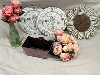 Garden decor lot including Royal Haeger vase, wooden plates, artificial flowers, metal basket and sunflower wall art shown on fabric background.