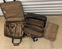 Photo showing open interior of the rolling luggage carry-on and work bag with organizer pieces laid out, highlighting the interior compartments and securing straps.
