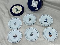 Overview of the six decorated canape plates arranged in front of the round, blue Paris-themed box.