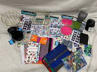 Photo showing assortment of school supplies including sticker sheets, sticky notes, wire baskets, zippered mesh organizers, notebooks, and small containers.