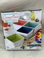 Box showing four square serving bowls with colored interiors and a white tray labeled 'Summertime Serving Set' new in box.