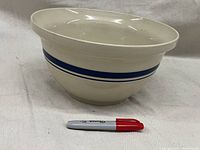 Angle view of the vintage ceramic mixing bowl with blue stripes and a Sharpie for scale.