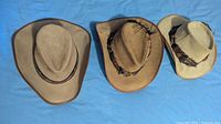 Three leather cowboy hats side by side showing colour and style