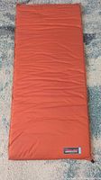 Full view of orange Therm-a-Rest self-inflating mattress pad laid flat on floor