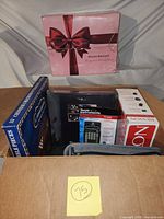 Overall view showing contents in open box including Chinese Checkers, TI-30XIIS, Revlon box, Dream Genius box