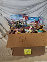 Box of assorted sealed toys showing major items