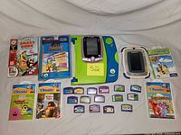 Full lot overview showing three electronic devices, books, cartridges and cases