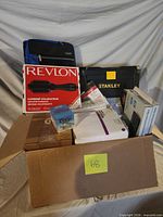 Overall lot view showing Revlon box, Stanley toolbox, keyboard box, binder, linen and other items