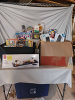 Overall lot on table: black tote with games, Home Depot box with keyboard, filters, toy, envelopes