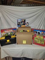 Overview with Stanley tool box, cardboard box of toys, Lego City set, ride-on toy case, floor puzzle