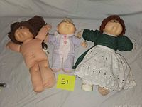 Three Cabbage Patch dolls laid out side by side.