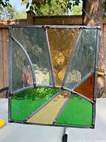 Front view of the stained glass suncatcher showing the abstract colored glass segments and soldered metal frame