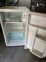 Open view of refrigerator interior showing freezer compartment with clear door, wire shelves, crisper drawer, and door storage sections.