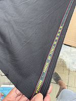 Selvedge edge showing “Loro Piana – Made in Italy” text and yellow star motif on black pinstripe fabric