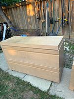 Full front view of solid wood dresser showing three deep drawers and removable top panel in an outdoor setting.