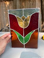 Front view of stained glass panel showing tulip design in multicolored glass with metal lead and frame