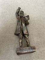 Front view of the sterling silver Rabbi figurine showing the raised right hand (missing a piece) and holding a book in the left hand, standing on a rectangular base.
