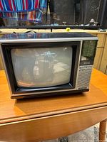 Front view of the vintage Hitachi CT1325 color TV powered on, showing screen and controls.