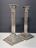 Front view of the pair of vintage silver plated Godinger candle holders showing fluted columns, Corinthian style capitals, and stepped square bases.