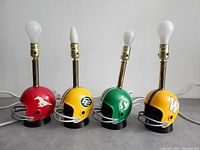 Front view of four CFL helmet lamps unlit, arranged in team order left to right.