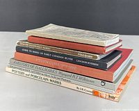 Stack of eight vintage guide books related to silver hallmarks, canadian silver, pottery and porcelain marks, and collectible marks.