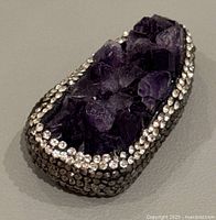 Close-up side perspective of natural amethyst cluster with rhinestones framing the edges.