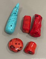 Photo showing all five pieces including one turquoise and four red coral pieces on a grey surface