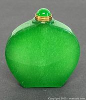 Front view of natural green jade perfume or snuff bottle; shows rich green mottled texture and domed jade cap with brass collar.