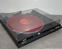 Technics SL-BD20A turntable with clear dust cover, red slipmat and visible front controls, taken from angled front view.
