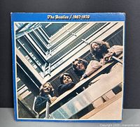 Front cover of The Beatles 1967-1970 Blue Album vinyl double record set. Shows the Beatles members looking down from a building with a blue border frame.