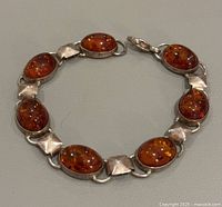 Top view showing the front of the bracelet with seven oval amber stones set in sterling silver with square silver links.