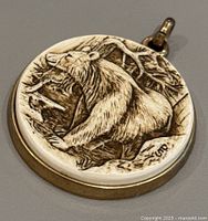 Front view of the vintage polar bear pendant showing detailed bear engraving and natural scene.