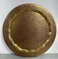 Front view of the large round vintage brass tray showing the hand chased floral and geometric designs with scalloped inner border.