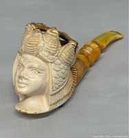 Close-up image of the carved meerschaum pipe showing the face and headdress detail.