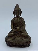 Front view of bronze-tone seated Buddha on lotus base