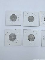 Four world coins in cardboard flips, one holed