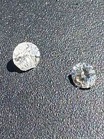 Two loose round brilliant diamonds on textured surface